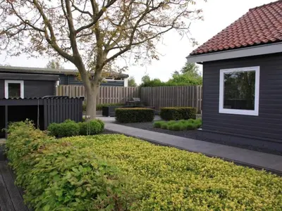 a backyard with a black house and a tree at Riverside holiday home near Amsterdam in Nigtevecht