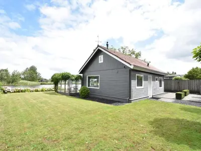 a small black house with a yard at Riverside holiday home near Amsterdam in Nigtevecht