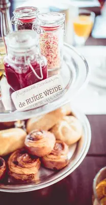 a plate of pastries and jars of jam on a table at Bed & Breakfast De Ruige Weide in Oudewater