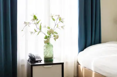 a vase with flowers on a table next to a window at Hotel Doria in Amsterdam