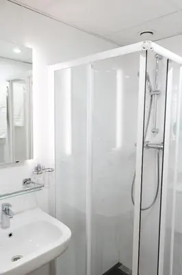 a white bathroom with a shower and a sink at Hotel Doria in Amsterdam