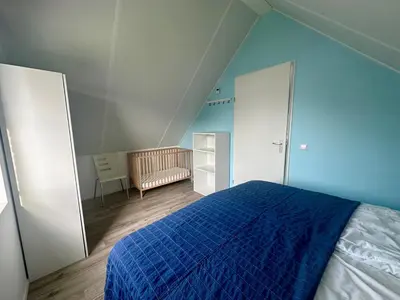 a blue bedroom with a bed with a blue blanket at De Wielen 58 in Sint Maarten