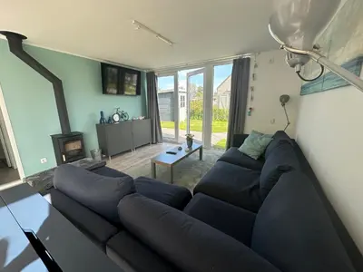 a living room with a black couch and a fireplace at De Wielen 58 in Sint Maarten