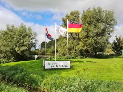 a sign with three flags on a field at Villa aan 't Wiel op Recreatiepark De Wielen in Sint Maarten
