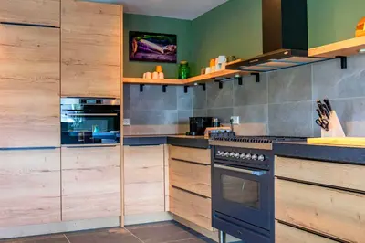 a kitchen with wooden cabinets and a stove at Villa aan 't Wiel op Recreatiepark De Wielen in Sint Maarten