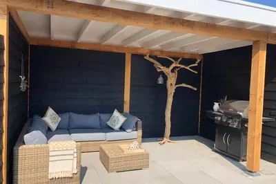 a patio with a blue couch and a tree at Country house between Egmond aan Zee & Amsterdam in Castricum
