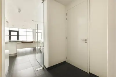 a room with white walls and a glass door at Appartement met frontaal zeezicht in Bloemendaal in Bloemendaal