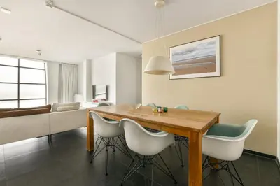 a dining room with a wooden table and chairs at Appartement met frontaal zeezicht in Bloemendaal in Bloemendaal