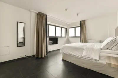 a white bedroom with a bed and a window at Appartement met frontaal zeezicht in Bloemendaal in Bloemendaal