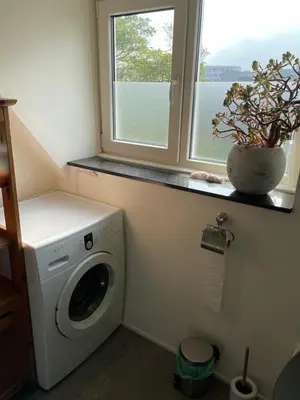 a laundry room with a washing machine and a window at Cosy appartment in Alkmaar