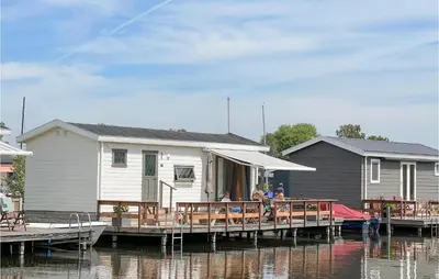 a group of people sitting on a dock next to a house at 2 Bedroom Lovely Home In Breukelen in Breukelen