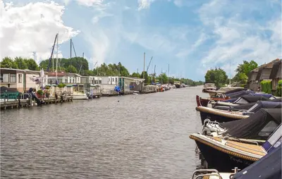 a group of boats docked on a river with houses at 2 Bedroom Lovely Home In Breukelen in Breukelen