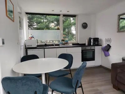 a kitchen with a white table and blue chairs at Huize Visser in Egmond aan Zee