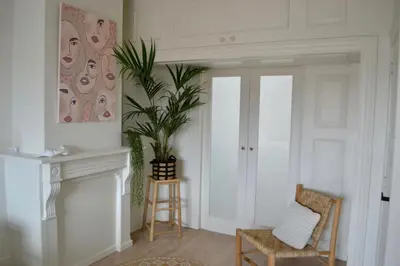 a living room with a potted plant and a chair at Oranje Nassau aan Zee Appartement in Zandvoort