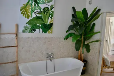 a bathroom with a white tub and a plant at Oranje Nassau aan Zee Appartement in Zandvoort