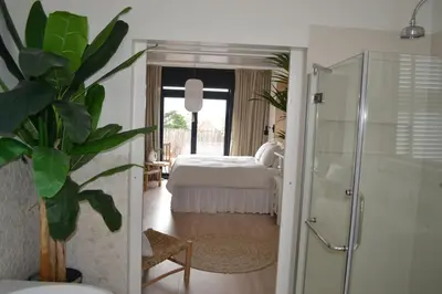 a bedroom with a bed and a glass shower at Oranje Nassau aan Zee Appartement in Zandvoort