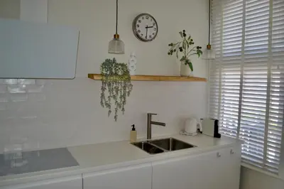 a kitchen with a sink and a clock on the wall at Oranje Nassau aan Zee Appartement in Zandvoort