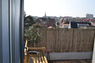 a balcony with a wooden fence and a wooden chair at Oranje Nassau aan Zee Appartement in Zandvoort