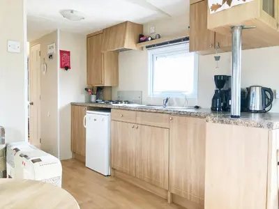 a kitchen with wooden cabinets and a white dishwasher at Chalet 575 op Recreatiepark De Wielen in Sint Maarten