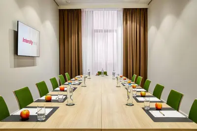 a long boardroom with a long table and green chairs at IntercityHotel Amsterdam Schiphol Airport in Hoofddorp