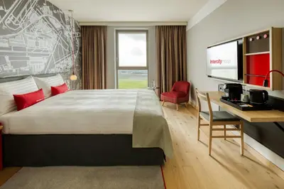 a hotel room with a bed and a desk and a television at IntercityHotel Amsterdam Schiphol Airport in Hoofddorp