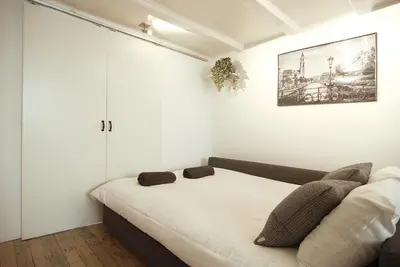 a white bedroom with a bed with pillows on it at Cosy apartment right in the city center with AIRCO! in Amsterdam