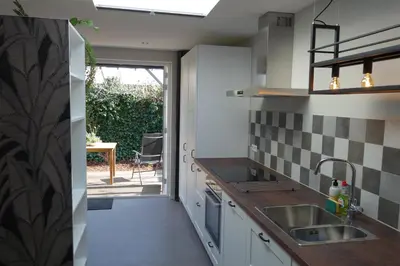 a kitchen with white cabinets and a sink at Quetzal in Schoorl
