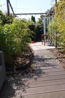 a wooden walkway with a bench in a garden at Quetzal in Schoorl
