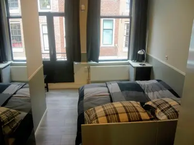 two beds in a room with two windows at ALDO, not for parties, not a hotel, room with shared bathroom, no kitchen in Amsterdam