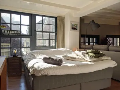 a large bed in a room with windows at LaneStay DamSquare in Amsterdam