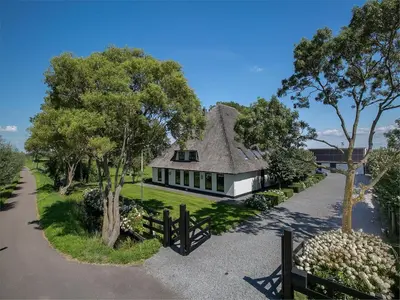 a white house with a roof with a fence at Spacious Holiday home De Pauwenhof in Heiloo