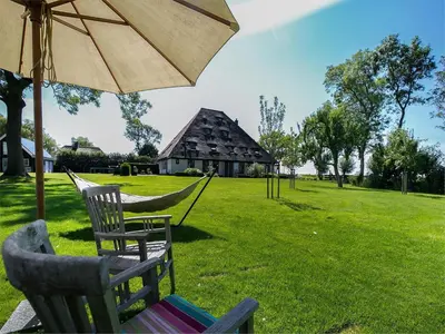 two chairs and a hammock in a yard with a building at Spacious Holiday home De Pauwenhof in Heiloo