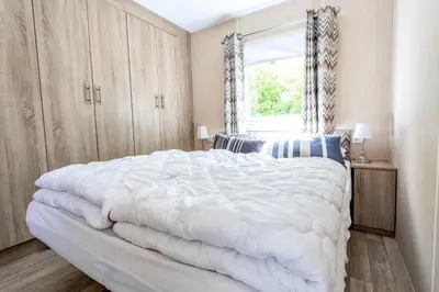 a bedroom with a large white bed with a window at Chalet 2a op Recreatiepark De Wielen in Sint Maarten