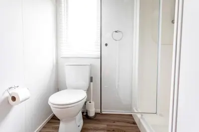a white bathroom with a toilet and a shower at Chalet 3a op Recreatiepark De Wielen in Sint Maarten