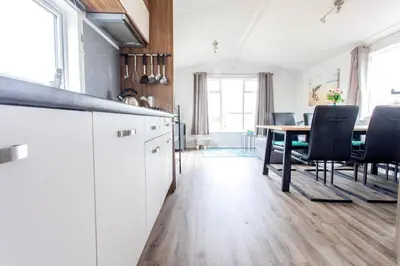 a kitchen with white cabinets and a table with chairs at Chalet 3a op Recreatiepark De Wielen in Sint Maarten