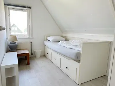 a white bedroom with a bed and a window at Bungalow 36 op Recreatiepark De Wielen in Sint Maarten