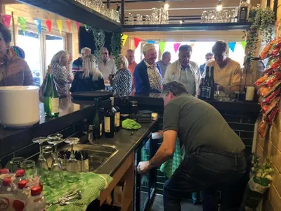 a group of people standing in a kitchen with a bartender at Bungalow 36 op Recreatiepark De Wielen in Sint Maarten