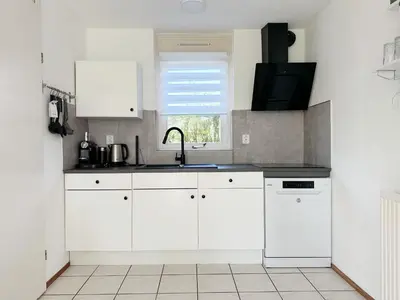 a kitchen with white cabinets and a sink and a window at Bungalow 36 op Recreatiepark De Wielen in Sint Maarten