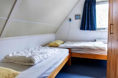 two beds in a small room with a window at Bungalow 40 op Recreatiepark De Wielen in Sint Maarten