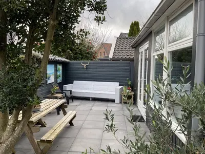 a patio with a white couch and a bench at Appelbloesem in Bergen