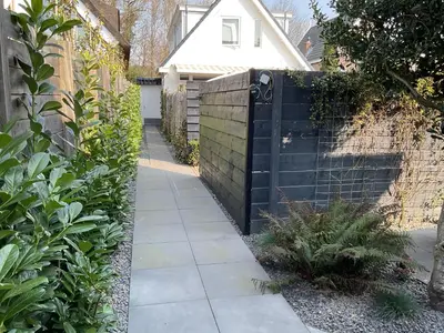 a garden with a black fence and a sidewalk at Appelbloesem in Bergen