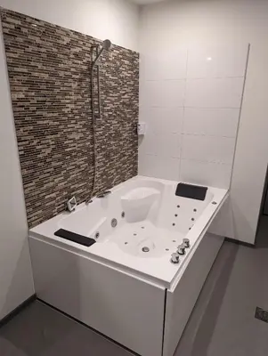 a white bath tub in a bathroom with a brick wall at Wellness Suite Utrecht in Utrecht