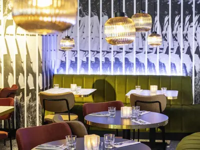 a restaurant with tables and chairs and chandeliers at Tribe Amsterdam City in Amsterdam
