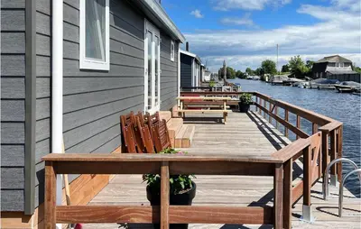 a wooden deck with benches and a house on the water at Gorgeous Home In Breukelen With Wifi in Breukelen