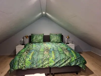 a bed with a green comforter in a attic at De Rokerij in Monnickendam