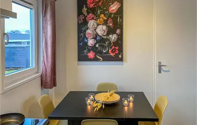 a dining room with a table with chairs and a painting at 2 Bedroom Awesome Home In Breukelen in Breukelen