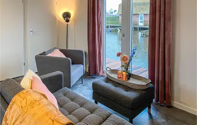 a living room with a couch and a table and a window at 2 Bedroom Awesome Home In Breukelen in Breukelen