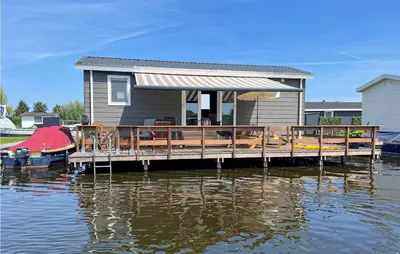 a house on a dock on a body of water at 2 Bedroom Awesome Home In Breukelen in Breukelen