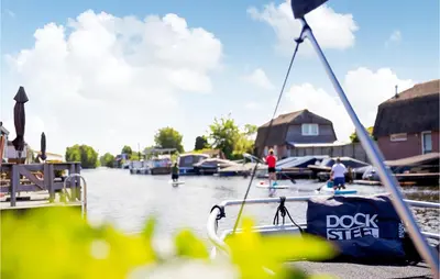a boat docked at a dock with people in the water at 2 Bedroom Awesome Home In Breukelen in Breukelen