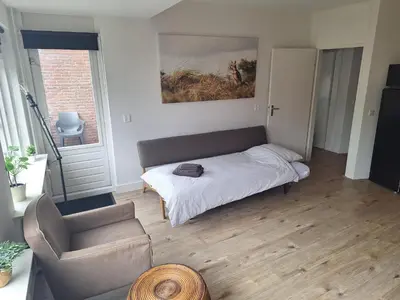 a living room with a bed and a chair at Have a nice stay! - Apartment Duinvos 150m from the beach in Noordwijk aan Zee